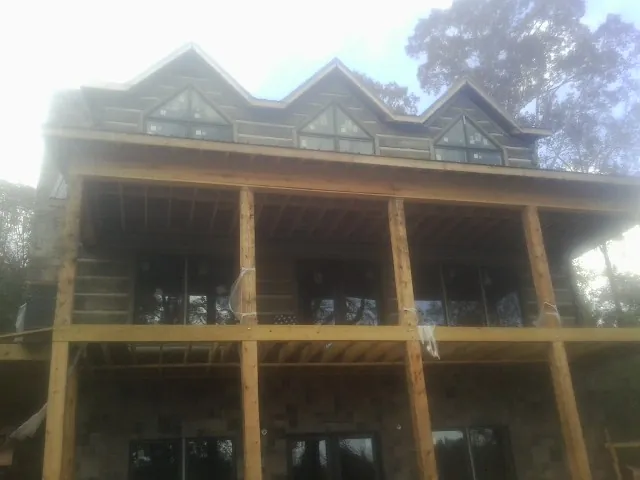 Dormers and porch framing on a large log home under construction — Roof Coating work by our crew in Marrero