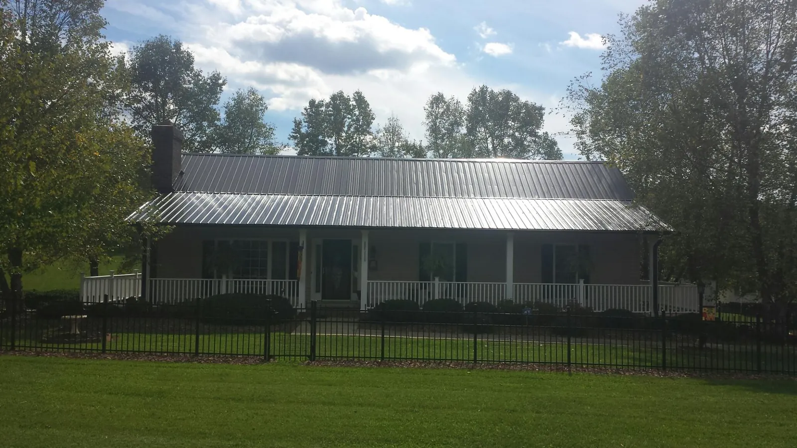 Gray metal roof on a brick ranch with a full width front porch — Gutter Guard Installation work by our crew in Marrero