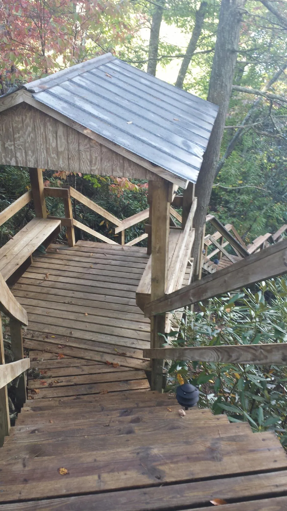 Metal roofed shelter over wooden steps on a wooded walkway — Skylight Repair & Installation work by our crew in Marrero