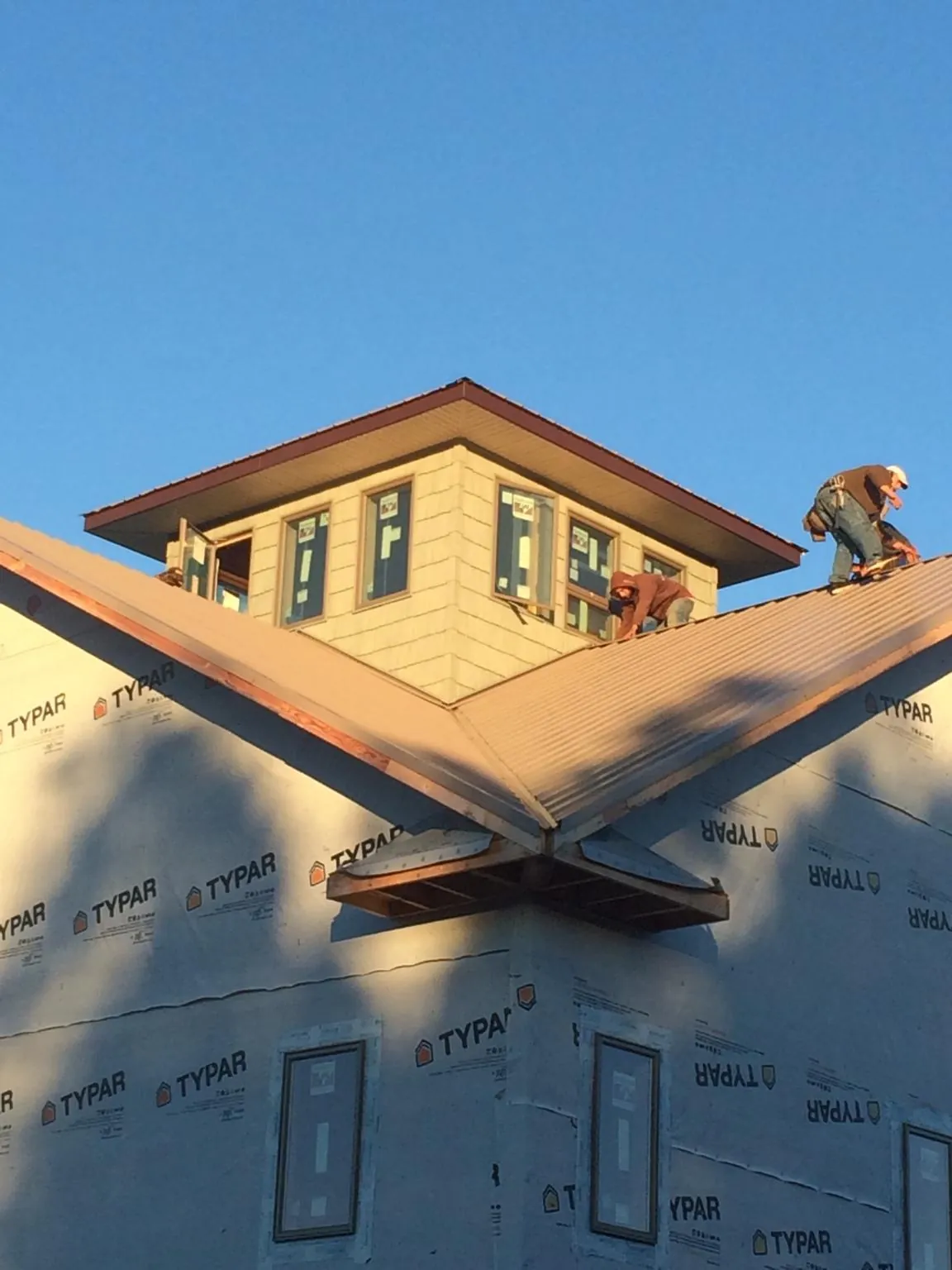 Roofers working around a rooftop cupola on a new metal roof at sunset — Roof Waterproofing in Marrero by Roofing Brothers